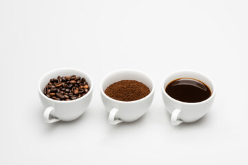 mugs with ground and prepared coffee near beans on white