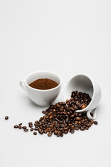 Fototapeta na wymiar beans and ground coffee in mugs on white