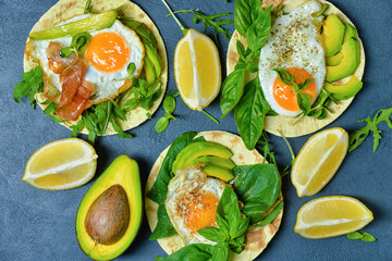 Tasty flatbread with egg and avocado on dark background