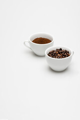 beans and ground coffee in cups on white