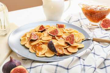 Plate with tasty mini pancakes and fig fruit on table