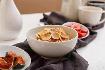 Bowl with tasty mini pancakes on table