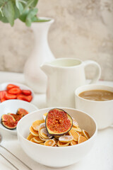 Bowl with tasty mini pancakes and fig fruit on table