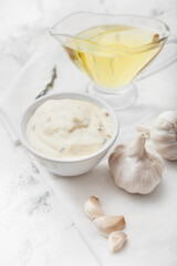 Bowl with garlic sauce and ingredients on white background