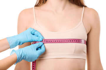 Doctor measuring size of young woman's breast against white background