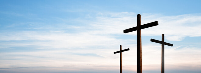 Easter concept. Cross of Jesus Christ empty over dramatic sunrise sky panorama with sclouds.
