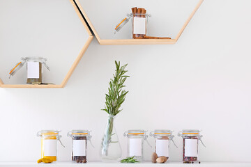 Jars with different spices on shelves in kitchen