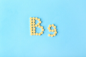 Text B9 made of folic acid pills on color background