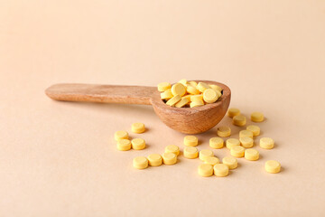 Spoon with folic acid pills on color background
