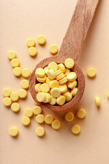 Spoon with folic acid pills on color background
