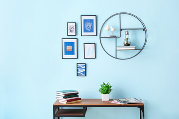 Books on table near color wall with stylish pictures