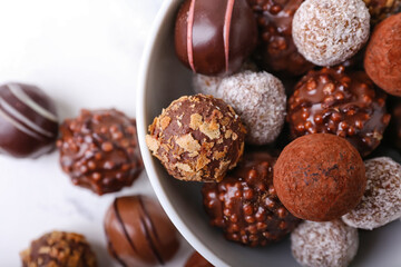 Bowl with sweet chocolate candies on light background, closeup