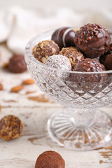Glass bowl with sweet chocolate candies on wooden background