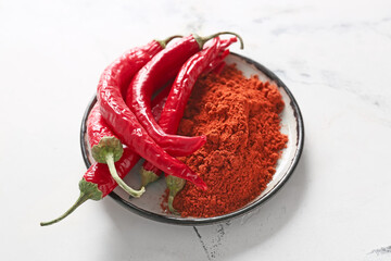 Plate with powder and chili peppers on light background