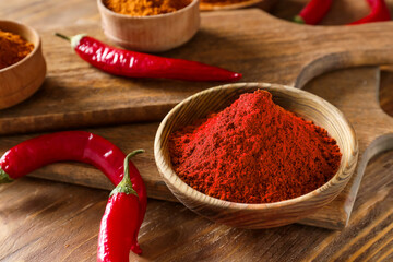 Bowls with red chili powder on wooden background