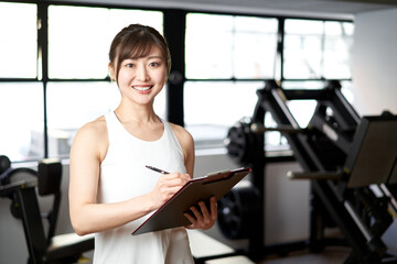 Fototapeta na wymiar トレーニングジムで笑顔で立つアジア人女性トレーナー