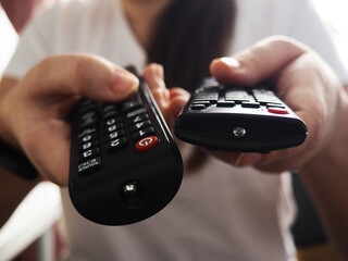 Hands holding the TV remote control, close-up at home