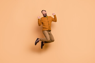 Full body portrait of astonished man fists up open mouth celebrate isolated on beige color background