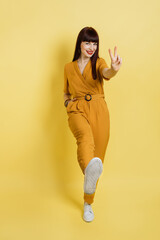 Number two, peace and victory sign. Young beautiful brunette woman wearing stylish ocher suit,...