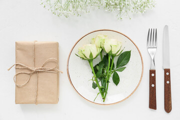 Beautiful table setting with gift on white background