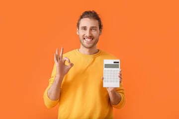 Young man with calculator showing OK gesture on color background - obrazy, fototapety, plakaty