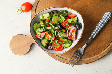 Bowl of fresh salad with vegetables on light background