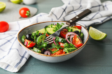 Bowl of fresh salad with vegetables on color wooden background