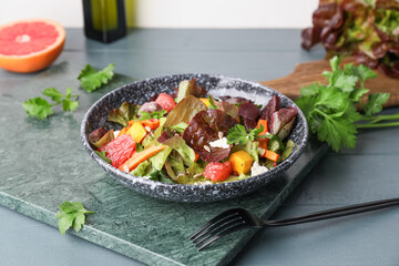 Bowl of fresh salad with vegetables on color wooden background