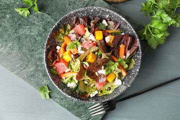 Bowl of fresh salad with vegetables on color wooden background