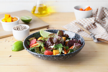Fototapeta na wymiar Bowl of fresh salad with vegetables on wooden background