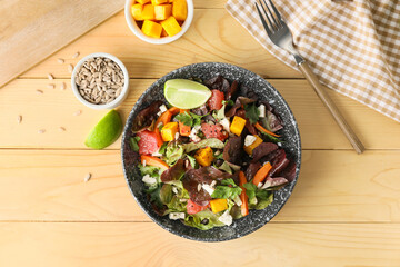 Bowl of fresh salad with vegetables on wooden background