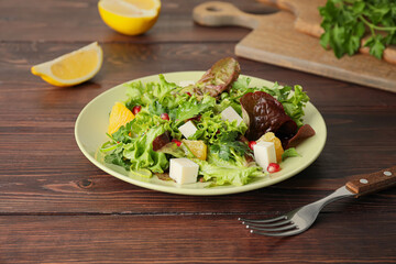 Plate of fresh salad with vegetables on wooden background