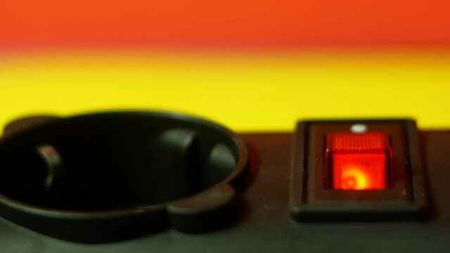 A close-up finger turns on the red power button of an electrical appliance. Red button to turn on / off the mains filter. Power supply to electrical household appliances. selective focus, shallow dept