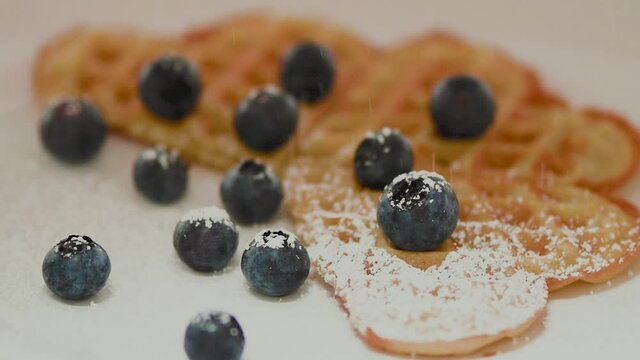 leckere, frische Waffel mit saftigen Blaubeeren wird mit Puderzucker best&auml;ubt.