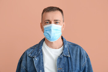 Mature man in medical mask on color background