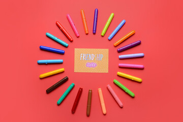 Markers and greeting card for Friendship Day on color background
