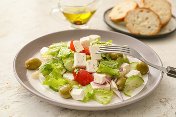 Plate with fresh Greek salad on light background, closeup