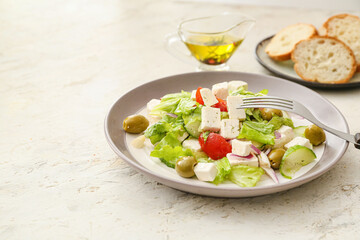 Plate with fresh Greek salad and slices of bread on light background