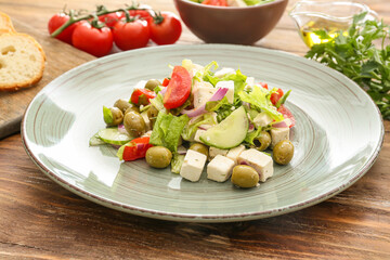 Plate with fresh Greek salad on wooden background, closeup