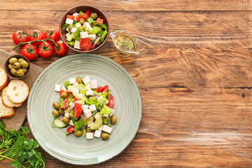 Composition with fresh Greek salad in plate on wooden background