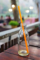 An empty orange juice bottle that was drank with a straw.