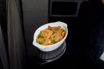 Casserole served in a glass dish filmed on a black background