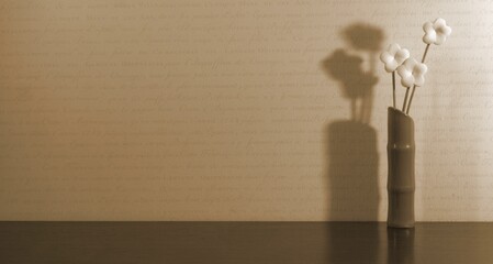 A vase of flowers in the corner on the table. Dimmed lights