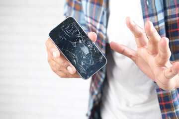 Close up of man hand holding broken smart phone.