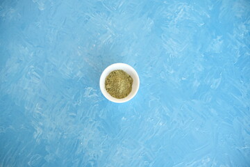 Fototapeta na wymiar Top view of organic matcha green tea in a bowl and matcha powder. Blue cheerful background.