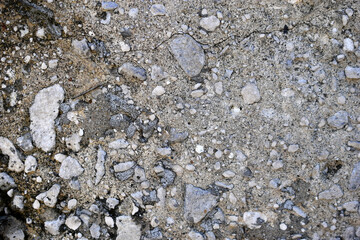 Stony gray concrete surface with pebbles and rubble