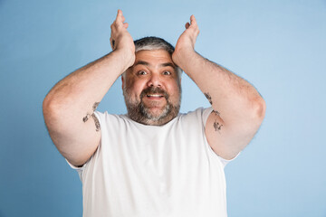 Handsome caucasian plus size male model isolated on blue studio background. Concept of inclusion, human emotions, facial expression