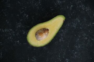 avocado on a black texture background. selective focus. Half of it. Healthy food.
