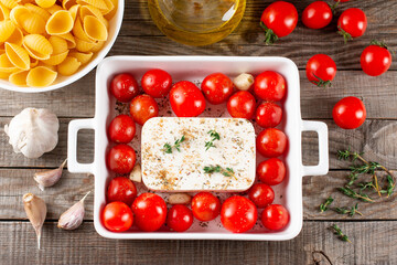Viral Feta bake pasta recipe with roasted cherry tomatoes, cheese, herbs and garlic isolated on a wooden table. Top view, above