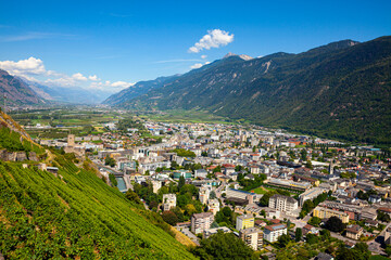 Fototapeta na wymiar Summer view from drone of Martigny town in green valley on banks of Rhone river surrounded by Alps, Switzerland.